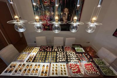 Table garnie de divers amuse-bouches colorés sous des suspensions lumineuses dans une salle à manger moderne.