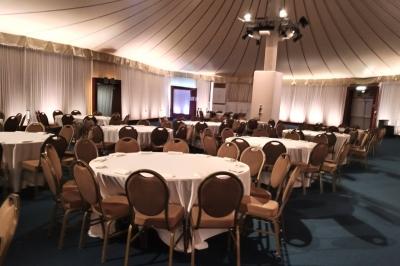 Salle de réception décorée avec des lumières colorées, des tables dressées et un éclairage tamisé.