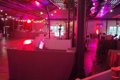 Salle de réception décorée avec des lumières colorées, des tables dressées et un éclairage tamisé.