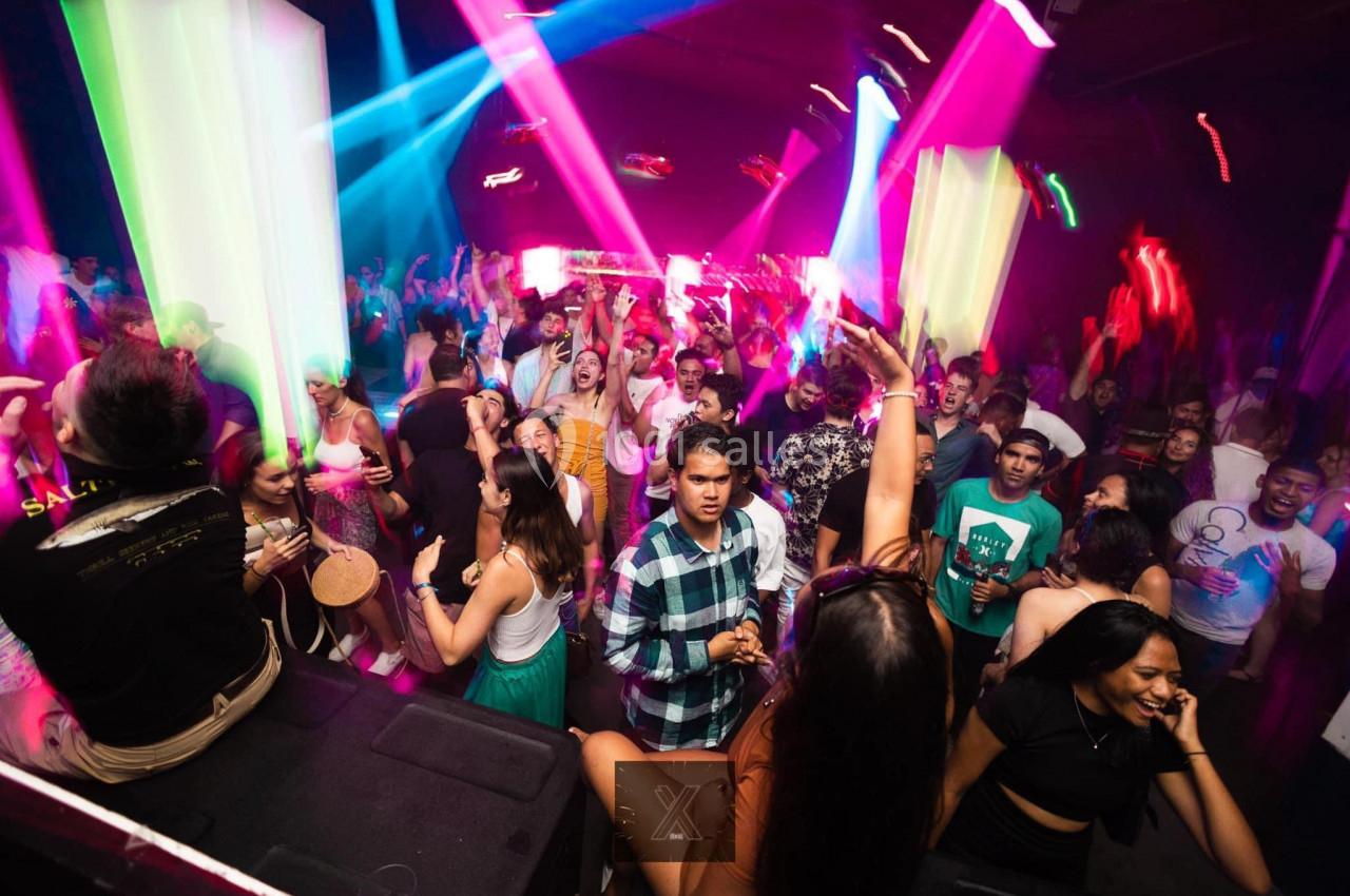 Personnes dansant et s'amusant dans une discothèque avec des lumières colorées et une ambiance festive.