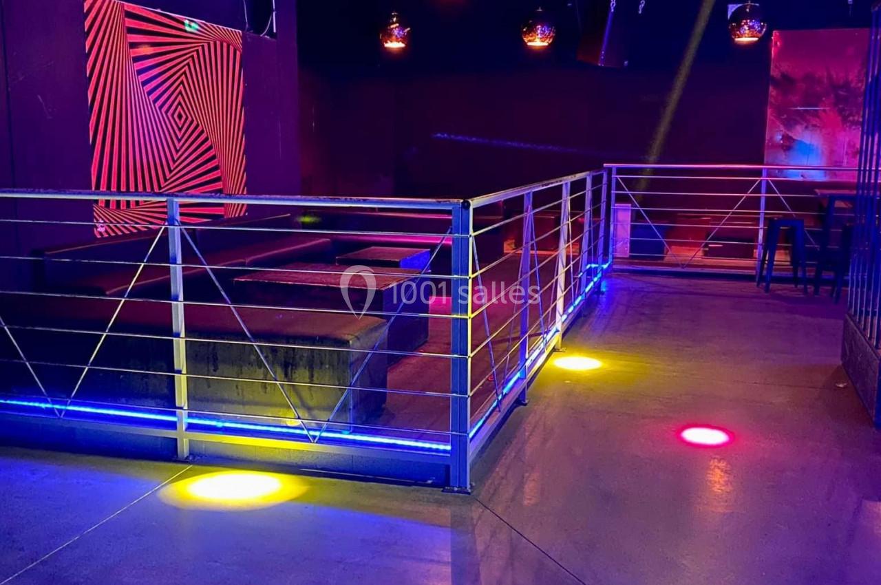 Salle vide avec piste de danse éclairée par des lumières colorées et décorations lumineuses au plafond.