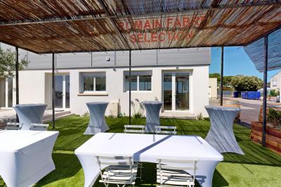 Salle de bain avec murs en carrelage beige, lavabo mural avec accessoires et toilettes séparées par une cloison.