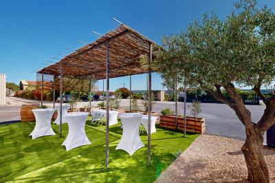 Salle de bain avec murs en carrelage beige, lavabo mural avec accessoires et toilettes séparées par une cloison.