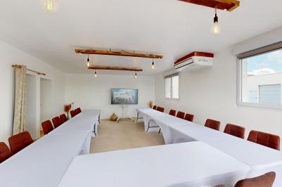 Salle de bain avec murs en carrelage beige, lavabo mural avec accessoires et toilettes séparées par une cloison.