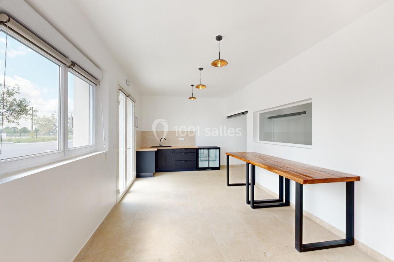 Cuisine minimaliste avec un plan de travail en bois, des luminaires suspendus et une grande fenêtre laissant entrer la…