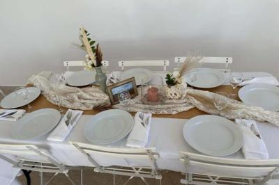 Salle de bain avec murs en carrelage beige, lavabo mural avec accessoires et toilettes séparées par une cloison.