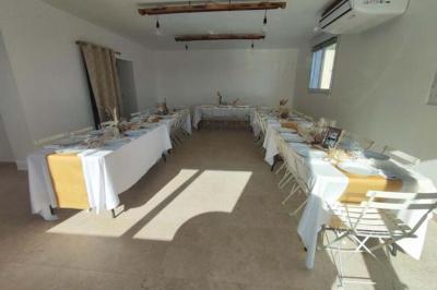 Salle de bain avec murs en carrelage beige, lavabo mural avec accessoires et toilettes séparées par une cloison.
