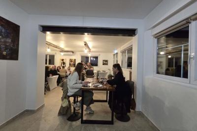 Salle de bain avec murs en carrelage beige, lavabo mural avec accessoires et toilettes séparées par une cloison.