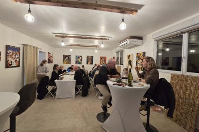 Salle de bain avec murs en carrelage beige, lavabo mural avec accessoires et toilettes séparées par une cloison.