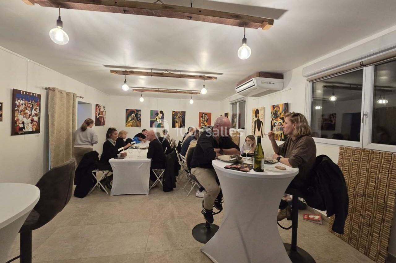 Des personnes dînent et discutent dans une salle lumineuse décorée de tableaux colorés.