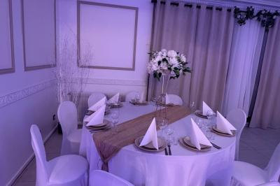 Enseigne lumineuse ’Baron’ entourée de verdure, avec des roses au premier plan et une façade éclairée en arrière-plan.