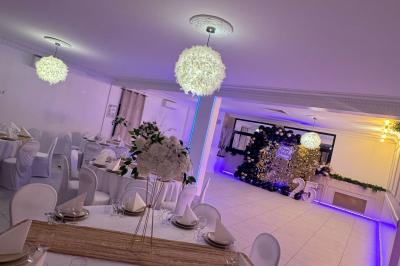 Enseigne lumineuse ’Baron’ entourée de verdure, avec des roses au premier plan et une façade éclairée en arrière-plan.