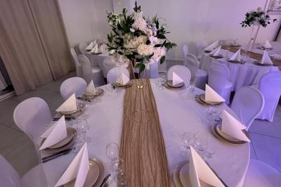 Enseigne lumineuse ’Baron’ entourée de verdure, avec des roses au premier plan et une façade éclairée en arrière-plan.