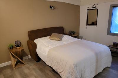 Miniature Location salle Peyruis (Alpes-de-Haute-Provence) - Les Grandes Mollières #22 Chambre lumineuse avec lit double, murs beige et blanc, parquet, miroir mural et table de chevet en bois.