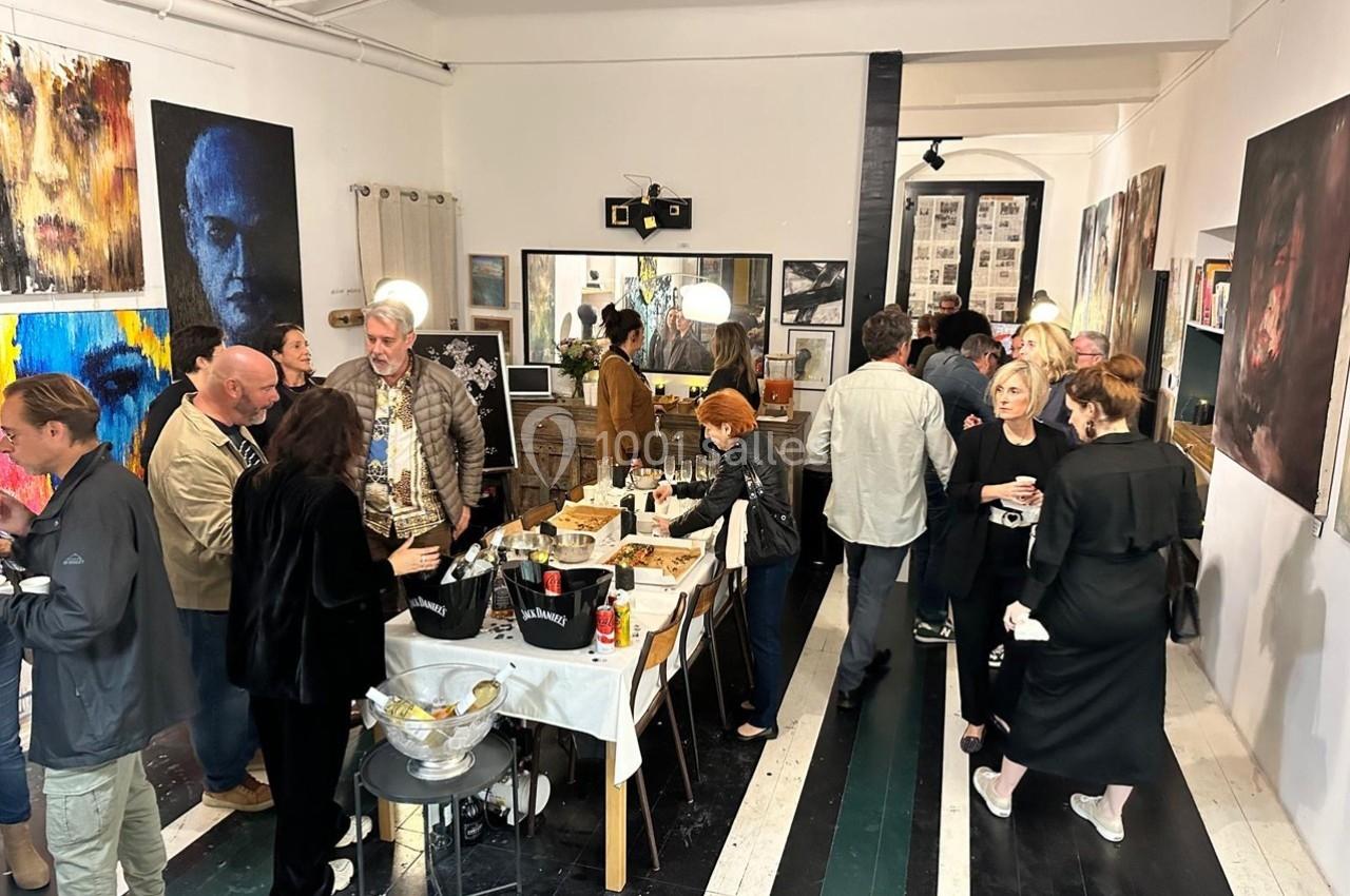 Des personnes discutent et partagent un moment convivial lors d'un vernissage dans une galerie d'art.