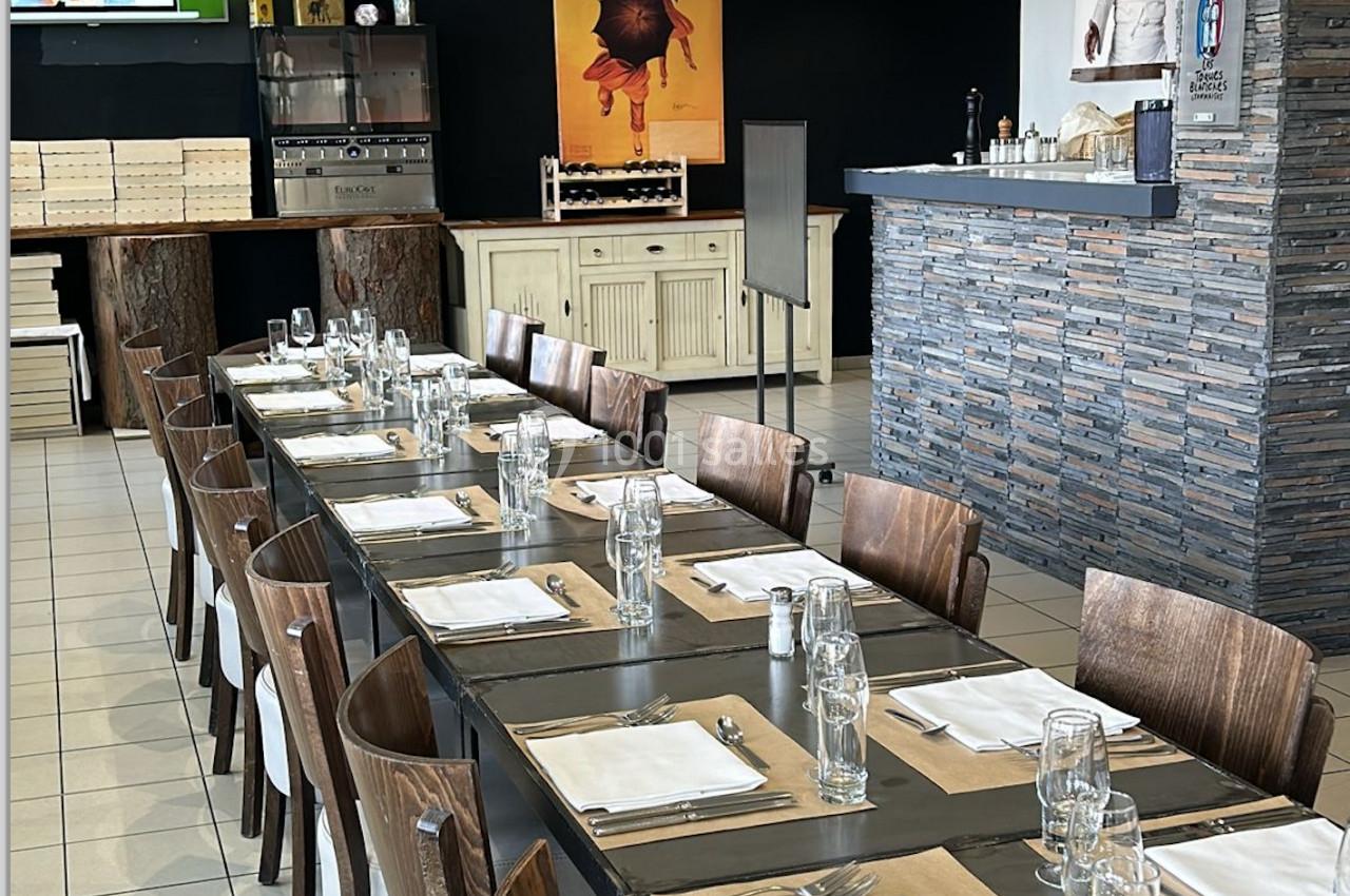 Grande table dressée avec des couverts et des verres dans un restaurant au décor moderne et chaleureux.