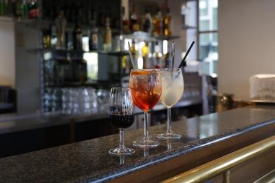 Salle lumineuse avec grandes baies vitrées, tables en bois et vue sur une rue calme bordée de bâtiments.