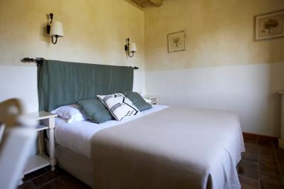 Vue d'une chambre cosy avec lit, éclairage doux, rideaux verts et table extérieure ornée de plantes et d'une tasse.