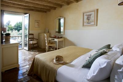 Vue d'une chambre cosy avec lit, éclairage doux, rideaux verts et table extérieure ornée de plantes et d'une tasse.