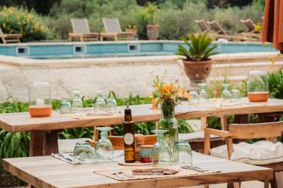Vue d'une chambre cosy avec lit, éclairage doux, rideaux verts et table extérieure ornée de plantes et d'une tasse.