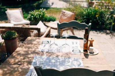 Vue d'une chambre cosy avec lit, éclairage doux, rideaux verts et table extérieure ornée de plantes et d'une tasse.