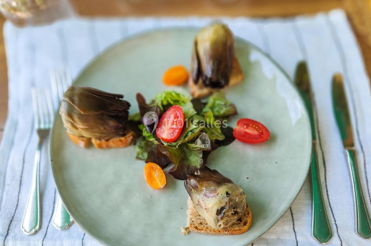 Assiette contenant des toasts aux artichauts, accompagnés de salade verte et de tomates cerises colorées.