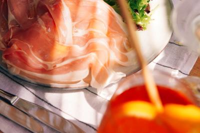 Vue d'une chambre cosy avec lit, éclairage doux, rideaux verts et table extérieure ornée de plantes et d'une tasse.