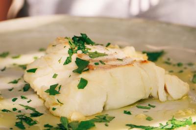 Vue d'une chambre cosy avec lit, éclairage doux, rideaux verts et table extérieure ornée de plantes et d'une tasse.