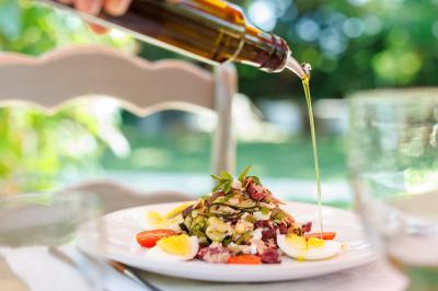 Vue d'une chambre cosy avec lit, éclairage doux, rideaux verts et table extérieure ornée de plantes et d'une tasse.