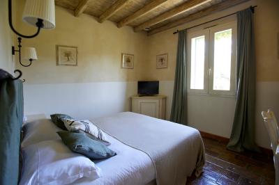 Vue d'une chambre cosy avec lit, éclairage doux, rideaux verts et table extérieure ornée de plantes et d'une tasse.
