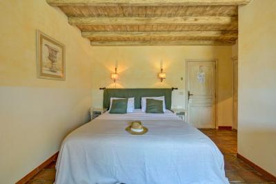 Vue d'une chambre cosy avec lit, éclairage doux, rideaux verts et table extérieure ornée de plantes et d'une tasse.