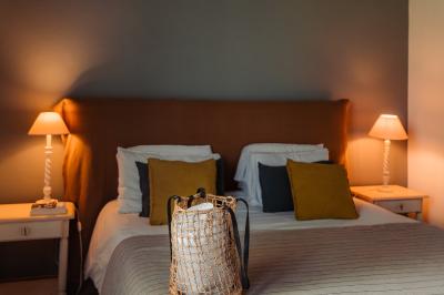 Vue d'une chambre cosy avec lit, éclairage doux, rideaux verts et table extérieure ornée de plantes et d'une tasse.