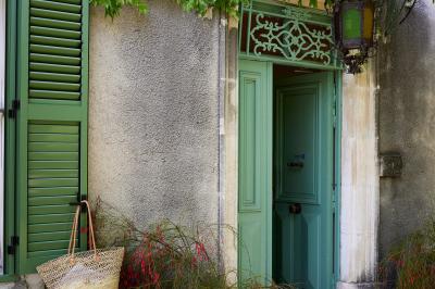 Vue d'une chambre cosy avec lit, éclairage doux, rideaux verts et table extérieure ornée de plantes et d'une tasse.