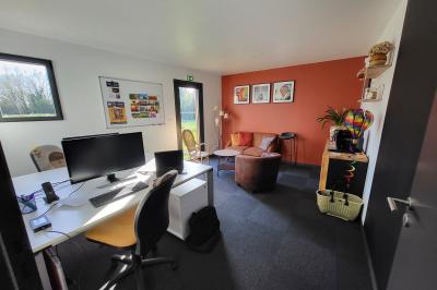 Vue aérienne d'une campagne verdoyante avec champs, haies, étangs et un village sous un ciel bleu dégagé.