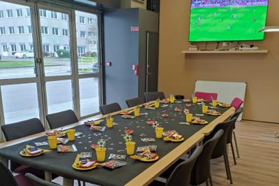 Table décorée pour une fête avec nappes noires, assiettes jaunes, gobelets, bonbons et motifs sur le thème du football.