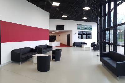 Façade illuminée du bâtiment Auxerrexpo de nuit, avec des visiteurs entrant et deux tracteurs exposés devant.