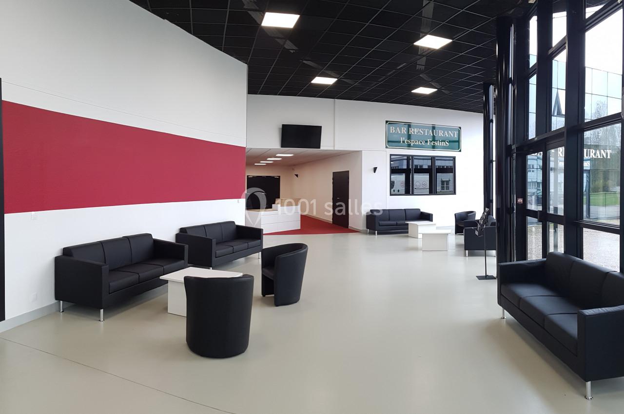 Espace d'accueil moderne avec canapés noirs, tables basses blanches et grande baie vitrée laissant entrer la lumière.