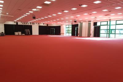 Façade illuminée du bâtiment Auxerrexpo de nuit, avec des visiteurs entrant et deux tracteurs exposés devant.