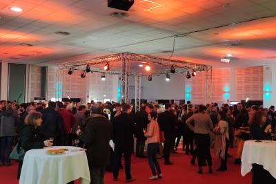 Façade illuminée du bâtiment Auxerrexpo de nuit, avec des visiteurs entrant et deux tracteurs exposés devant.