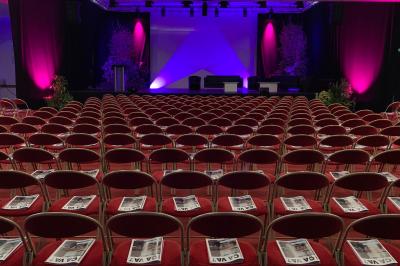 Façade illuminée du bâtiment Auxerrexpo de nuit, avec des visiteurs entrant et deux tracteurs exposés devant.