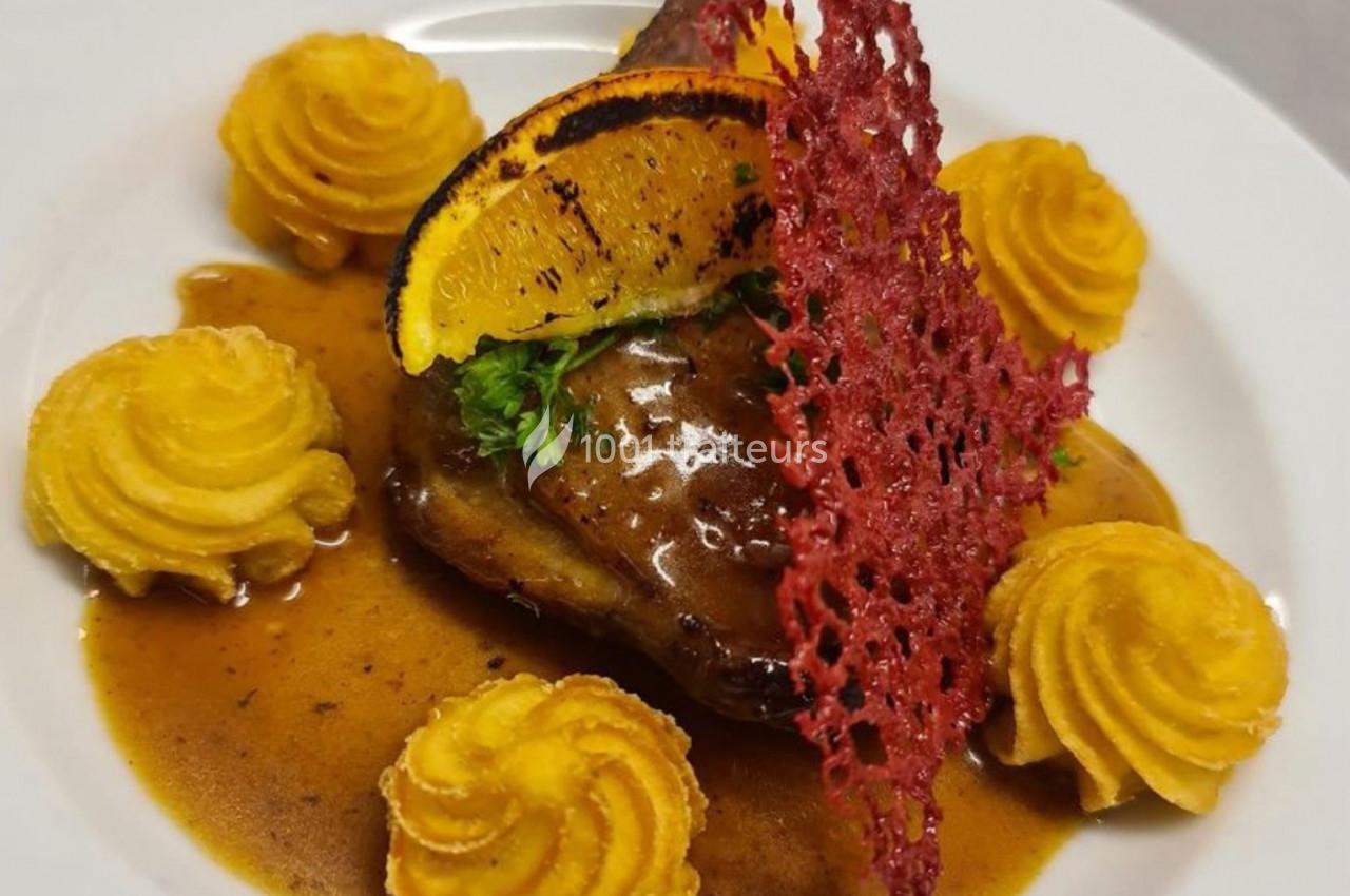 Assiette gastronomique avec viande en sauce, purée en rosaces, tranche d'orange grillée et tuile rouge décorative.