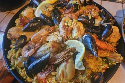 Assiette de fruits de mer variés avec moules, crevettes et quartiers de citron sur un lit de riz.
