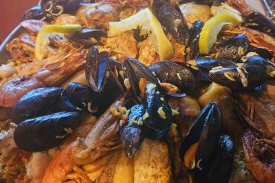 Assiette de fruits de mer variés avec moules, crevettes et quartiers de citron sur un lit de riz.