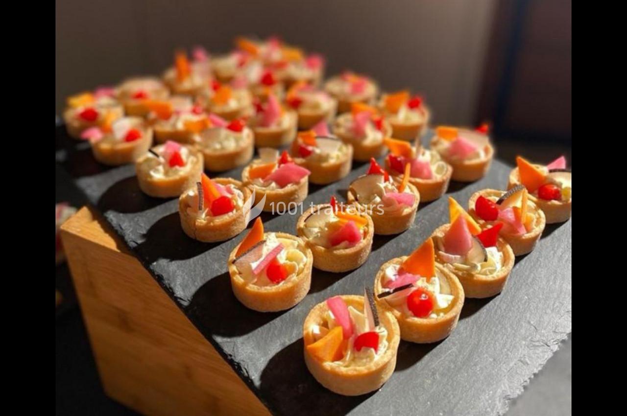 Plateau de petites tartelettes garnies de fruits colorés, disposées sur une ardoise noire.