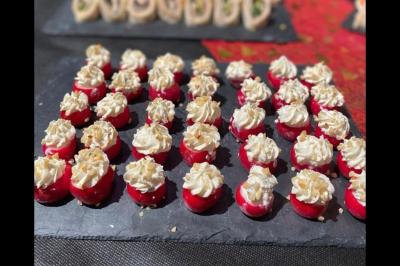 Radis farcis de fromage frais et noix concassées, disposés en rangées sur une ardoise noire.