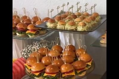 Plateaux de mini-burgers et bouchées apéritives présentés sur des supports en verre pour un buffet.
