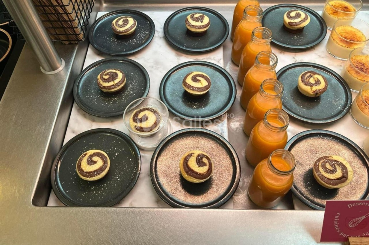 Desserts individuels en spirale chocolat-vanille sur assiettes noires, accompagnés de jus d'orange en bouteilles.