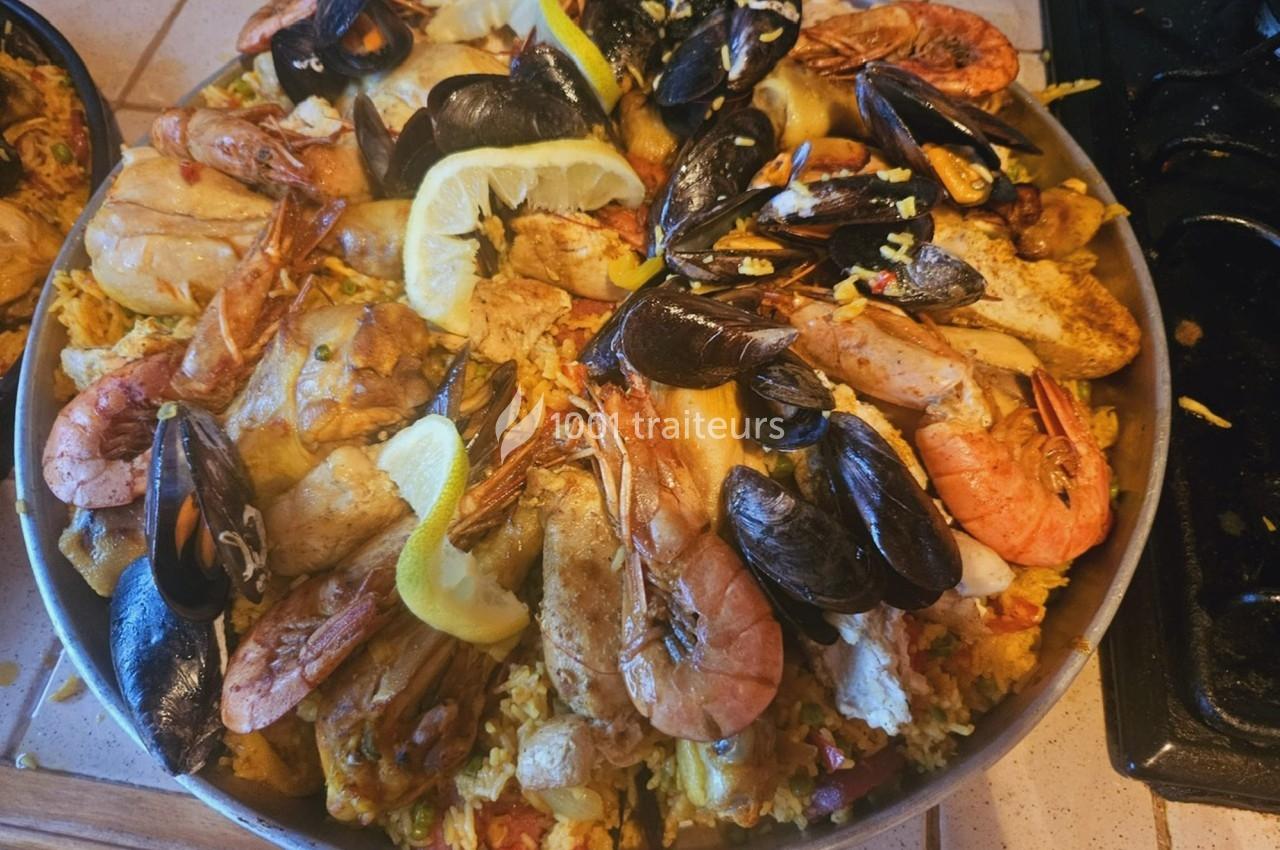 Plat de paella garni de fruits de mer, poulet, moules, crevettes et tranches de citron sur un lit de riz safrané.