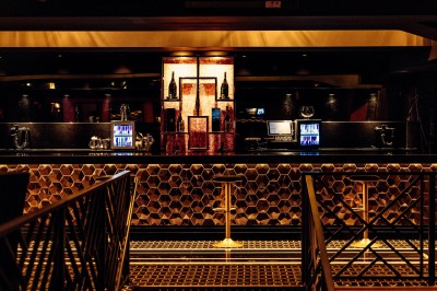 Intérieur d'une salle moderne avec mezzanine, éclairage tamisé, motifs géométriques au sol et écran lumineux au fond.
