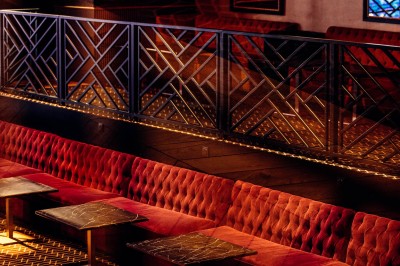 Intérieur d'une salle moderne avec mezzanine, éclairage tamisé, motifs géométriques au sol et écran lumineux au fond.